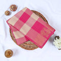 Venkatagiri cotton saree with pink and beige checkered pattern and gold zari border folded top view.