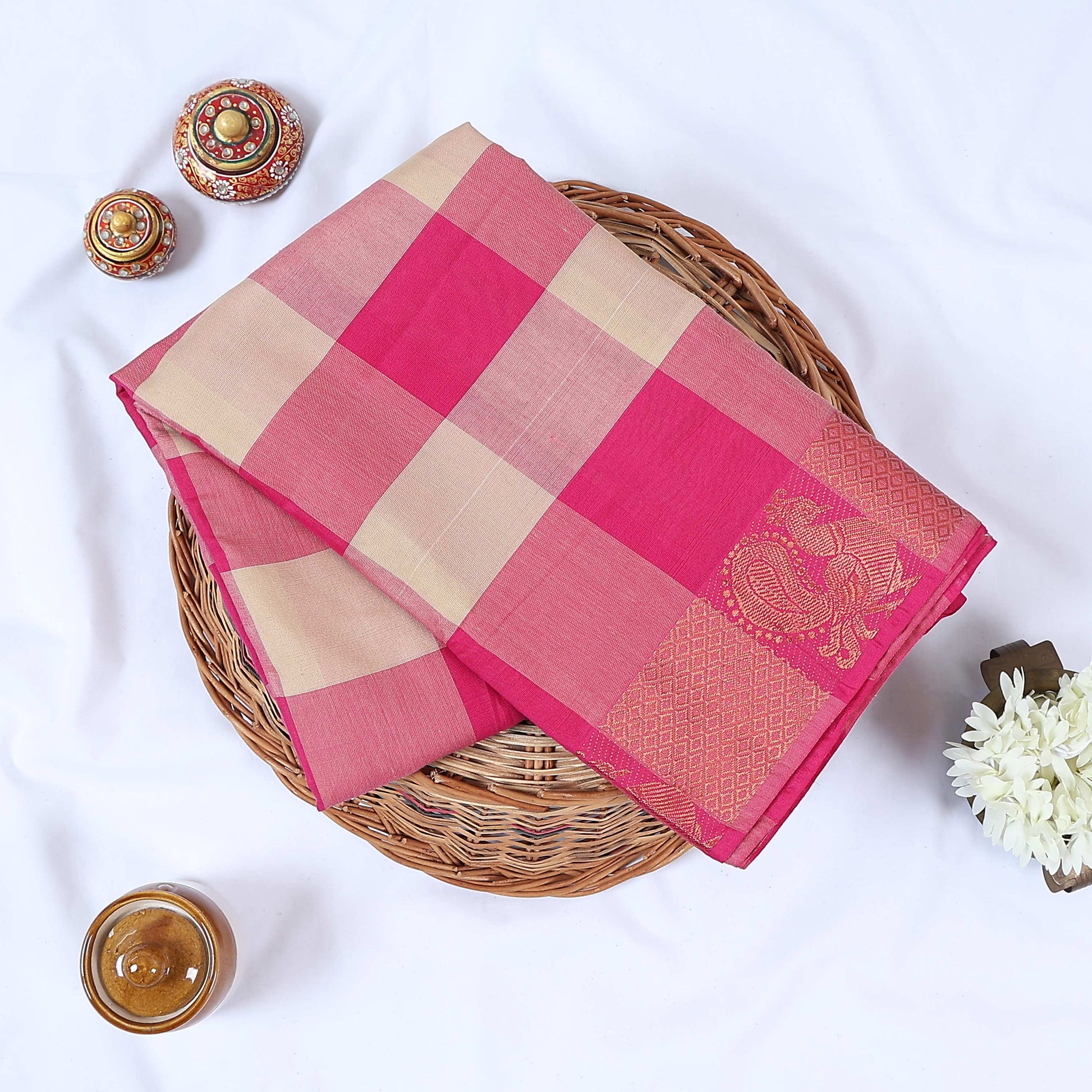 Venkatagiri cotton saree with pink and beige checkered pattern and gold zari border folded top view.