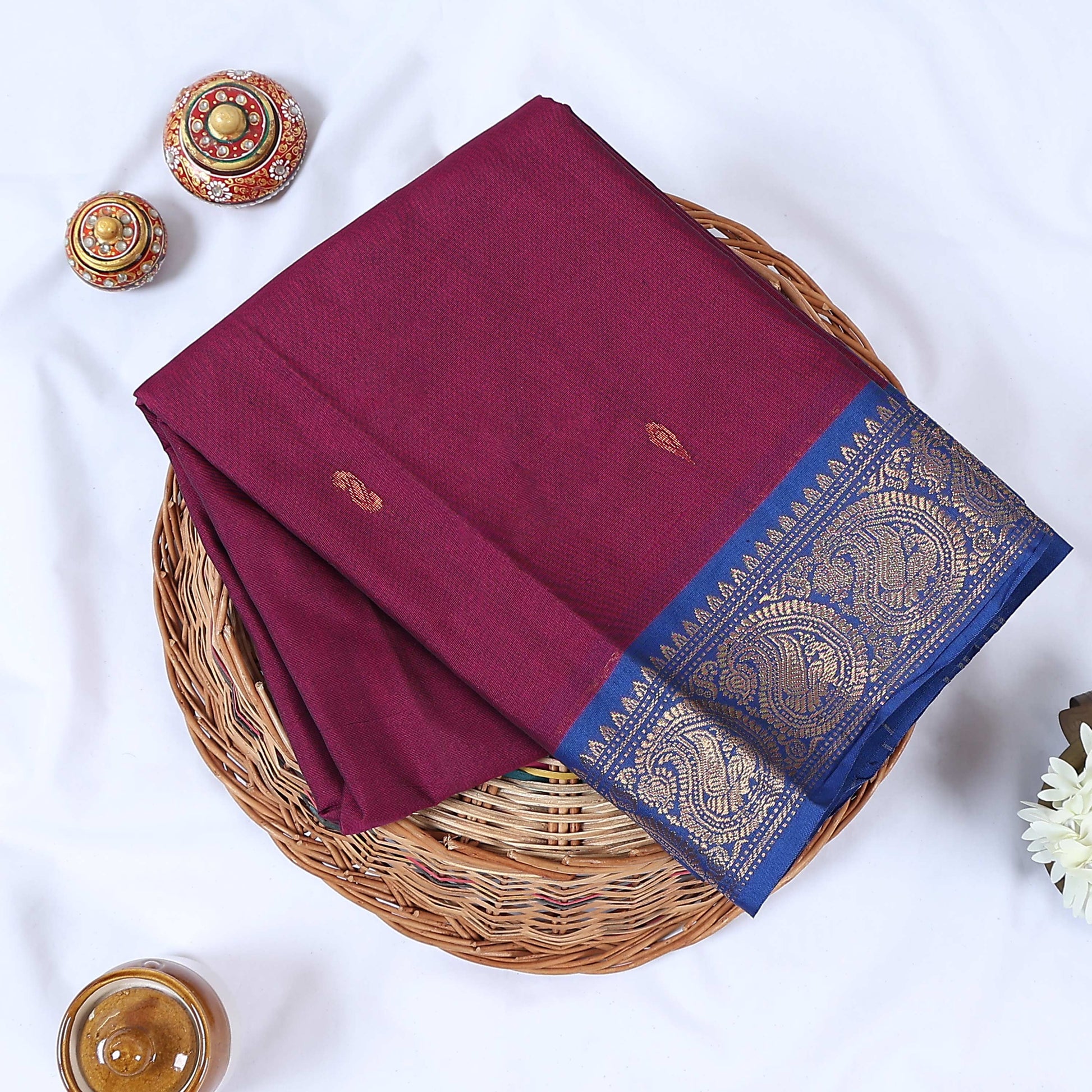 Venkatagiri cotton saree with small zari buttas purple body and royal blue paisley zari border folded top view.