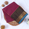 Venkatagiri cotton saree with gold stripes black zari border and blue edge folded top view on wicker tray.