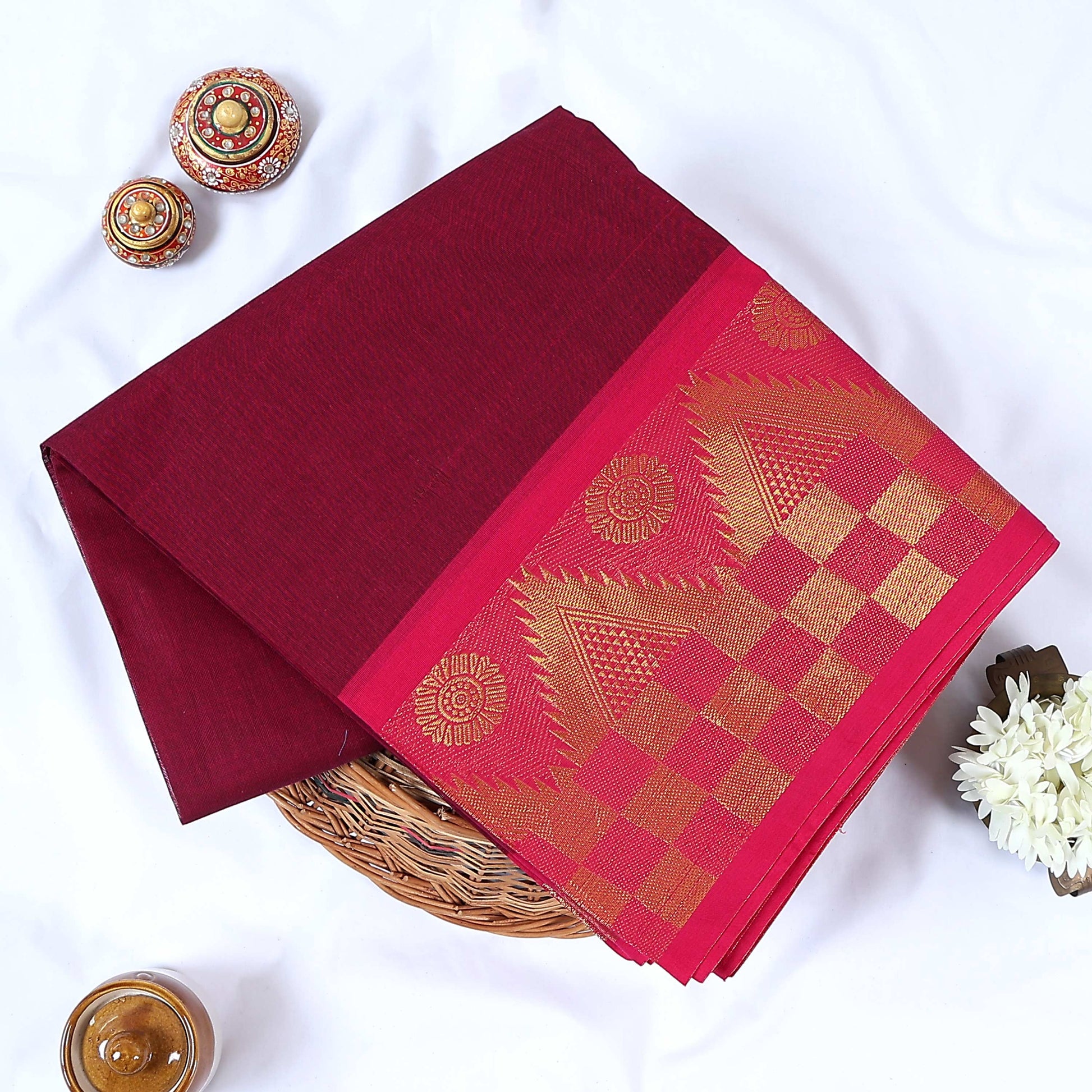 Venkatagiri cotton saree with maroon body pink geometric temple zari border folded top view with border details.