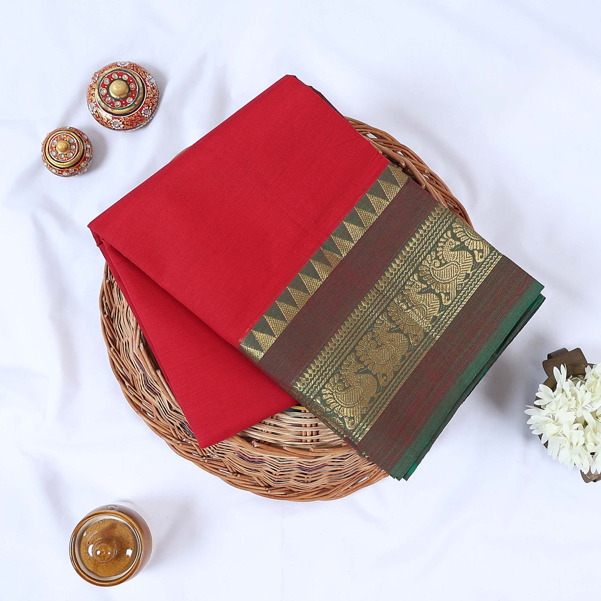 Venkatagiri cotton saree with red body olive green peacock zari border folded front view on wicker basket