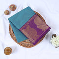 Venkatagiri cotton saree with teal blue body and purple gold zari peacock border folded top view.