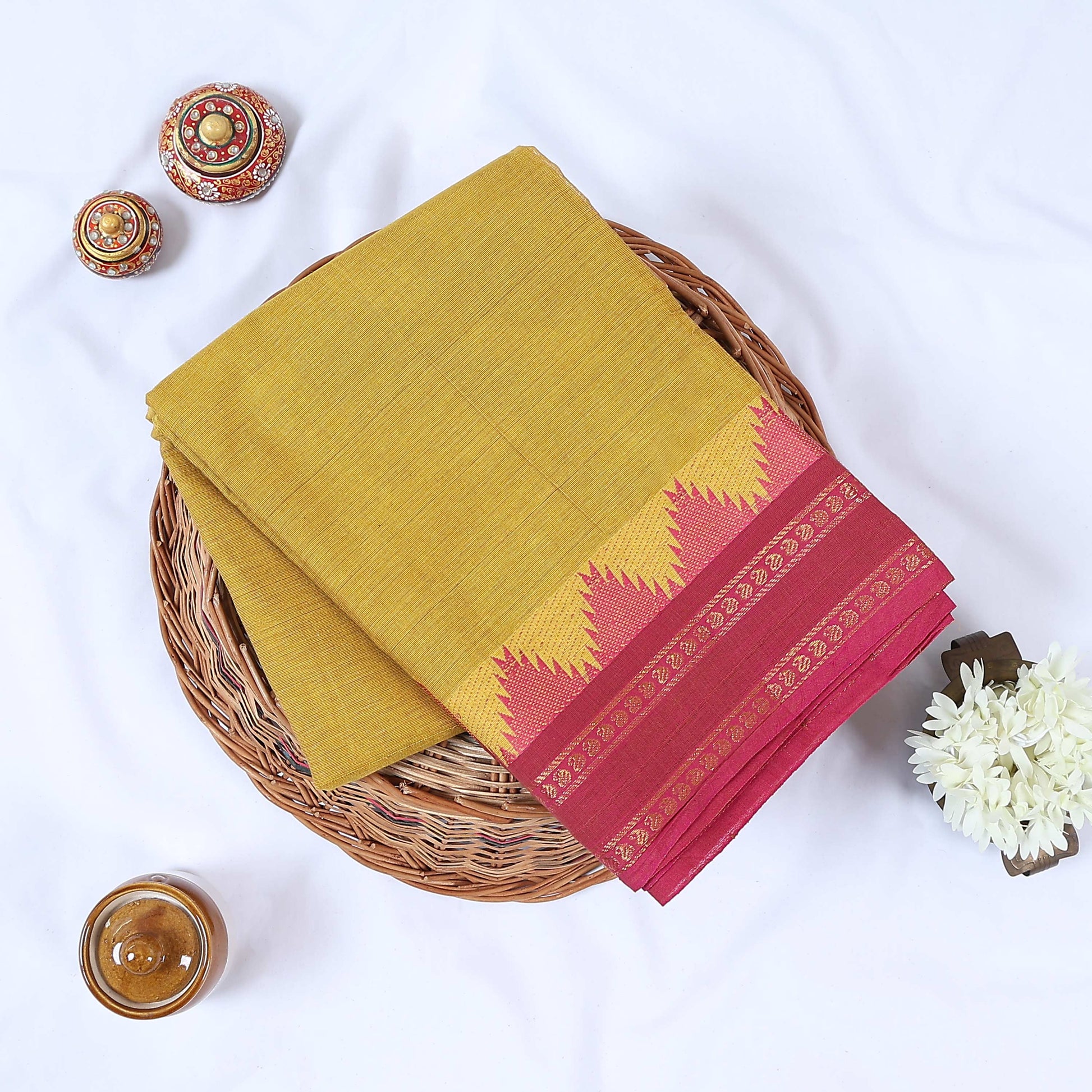 Yellow Venkatagiri cotton saree with pink zari temple border folded flat lay front view.