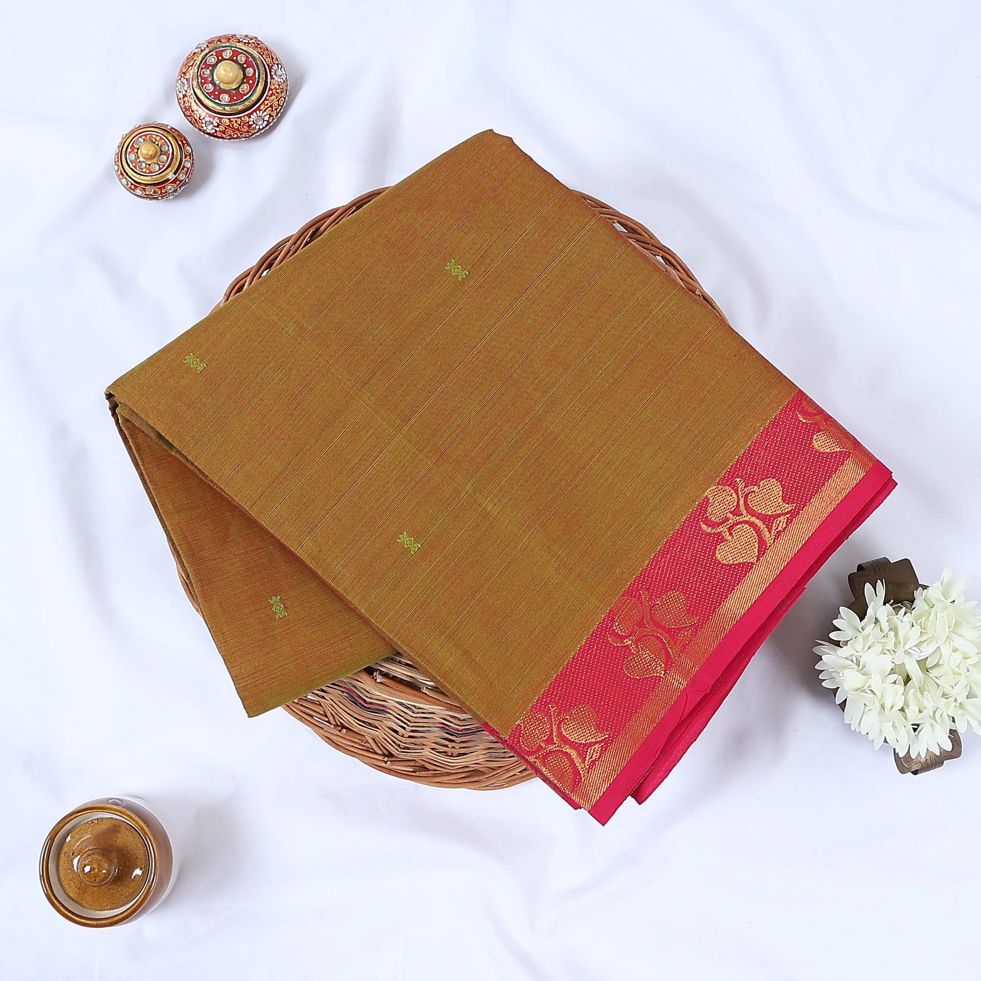 Venkatagiri cotton saree with plain olive green body floral zari pink border and butta motifs folded top view.