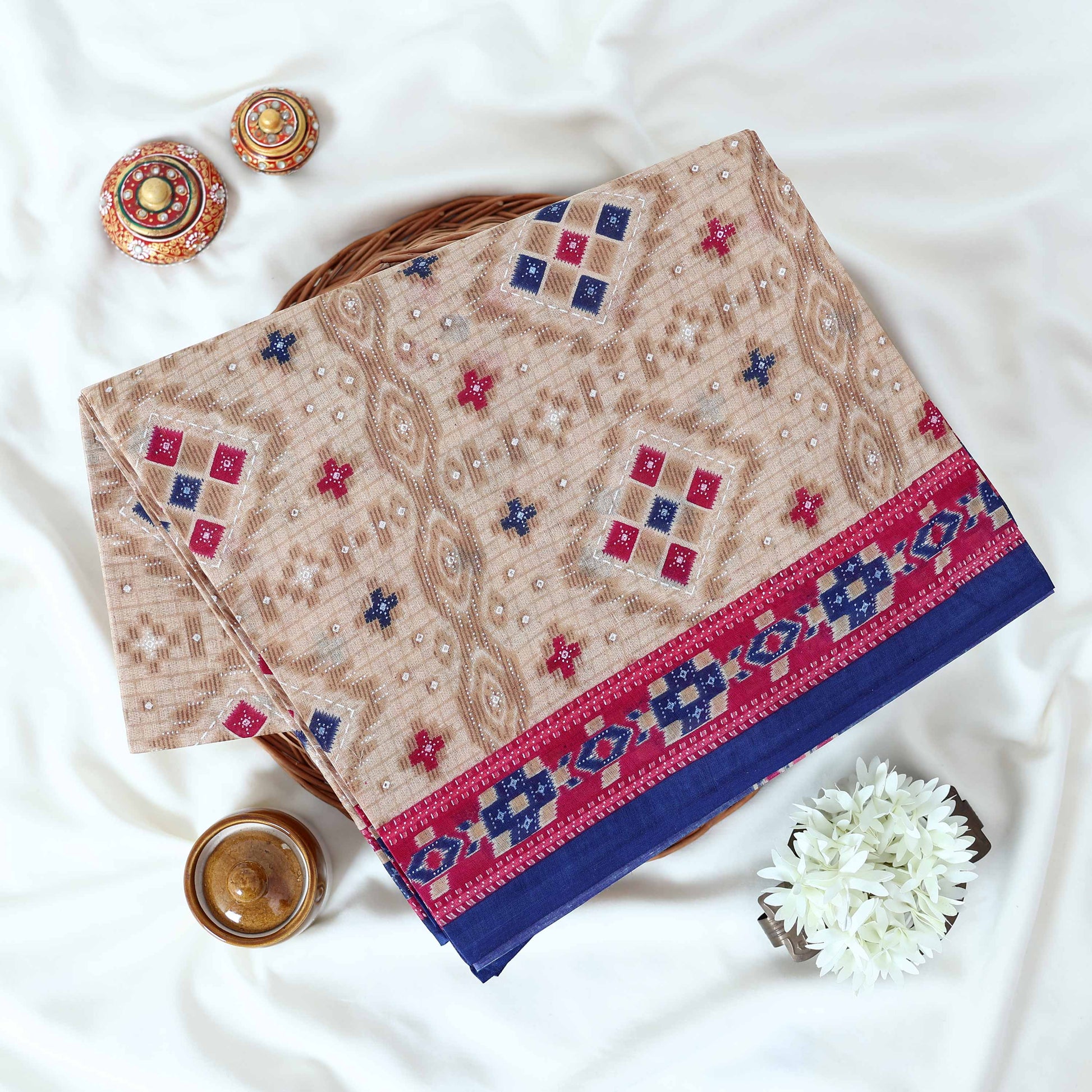 Voile cotton saree with beige geometric motifs and blue pink Ikat border folded display top view
