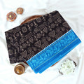 Black Voile cotton saree with tribal print body and blue contrast folk art border folded top view 