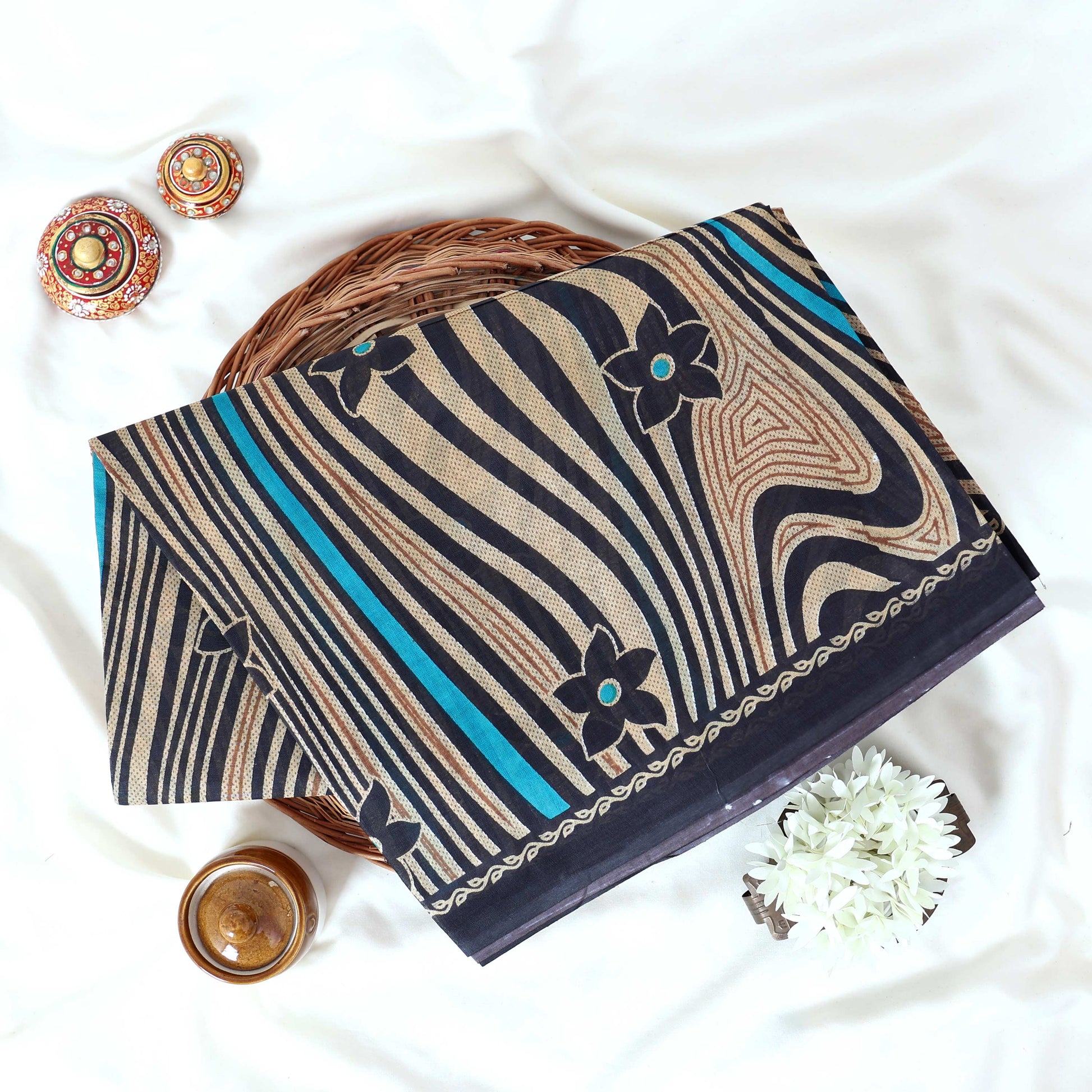 Voile cotton saree black floral motifs and wavy beige stripe pattern with blue accents top view.