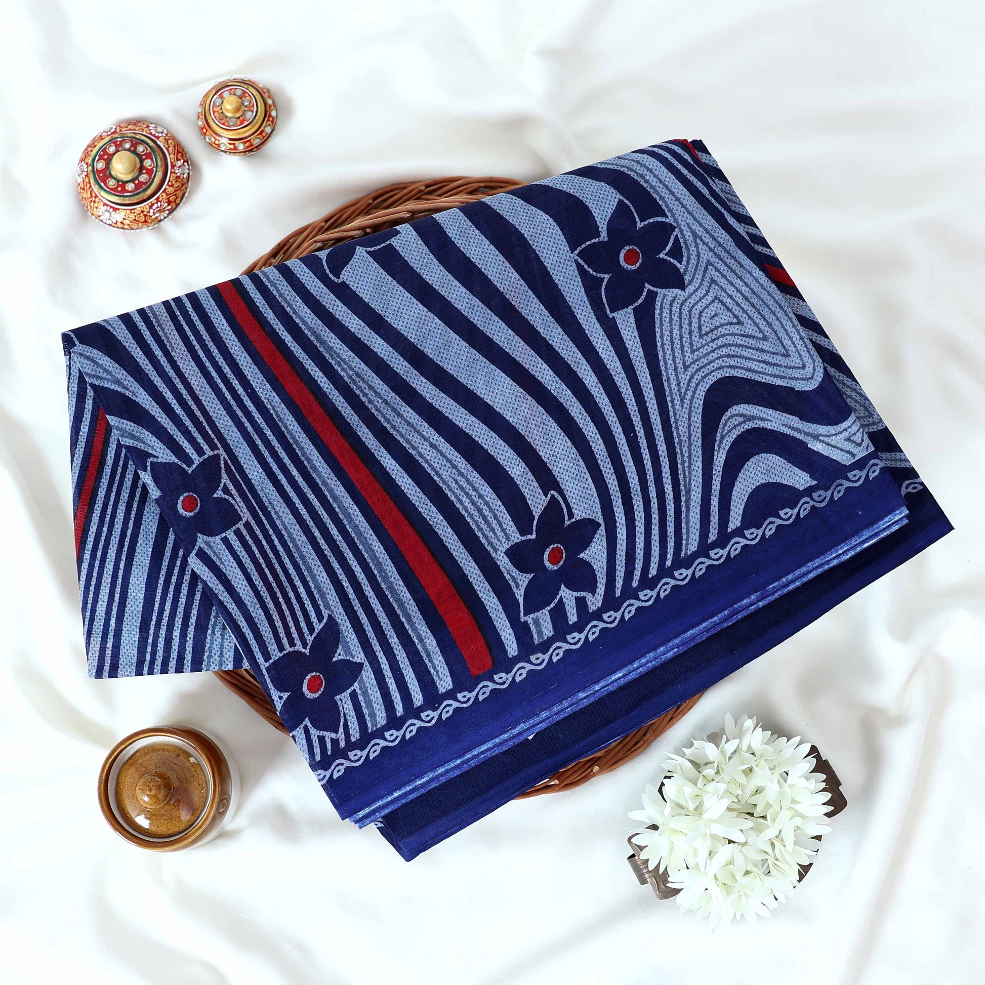 Voile cotton saree navy blue floral motifs and wavy white stripe pattern with red accents top view.