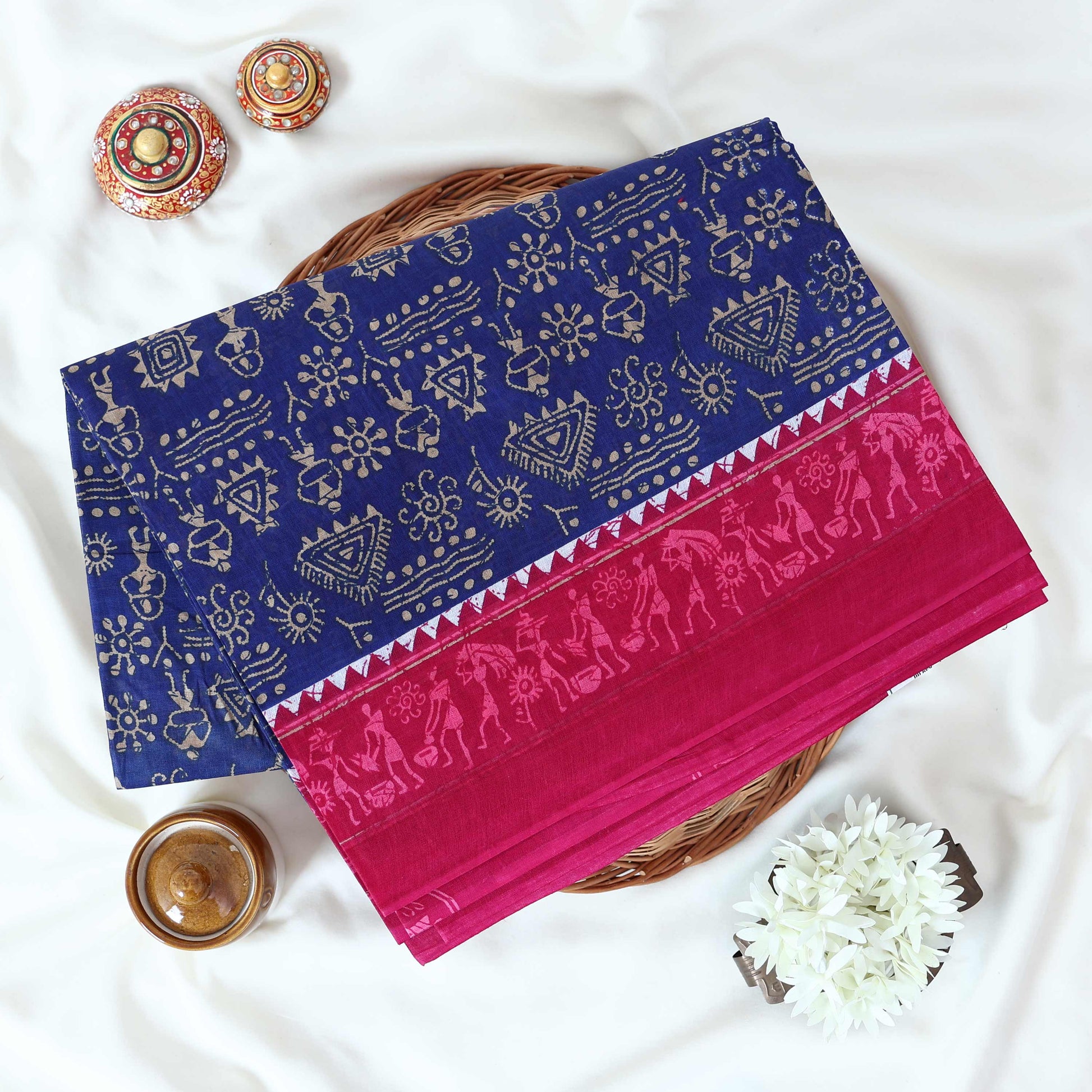 Blue Voile cotton saree with tribal print body and pink contrast folk art border folded top view 