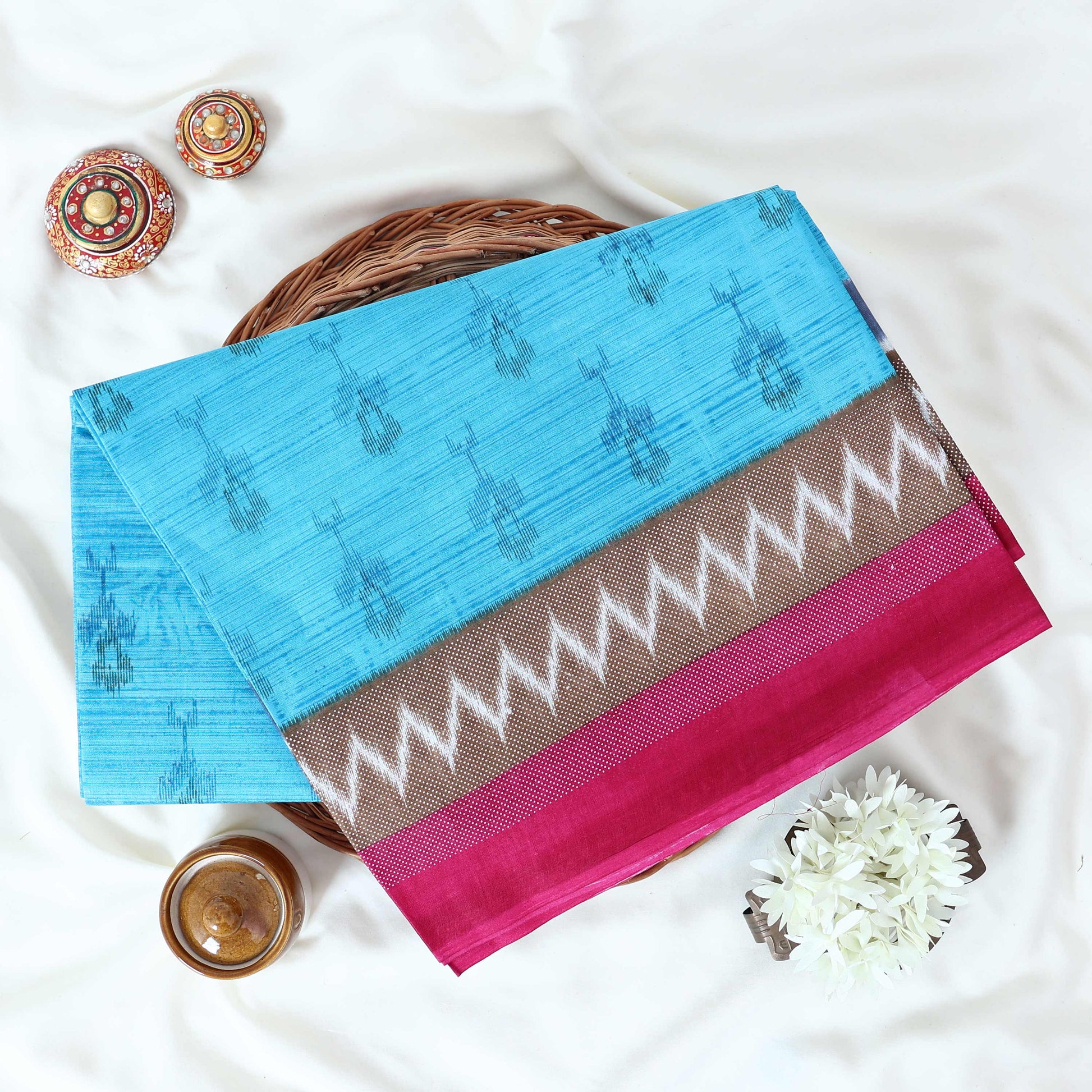 Blue voile cotton saree with ikat printed pattern and contrast chevron zari border folded top view display