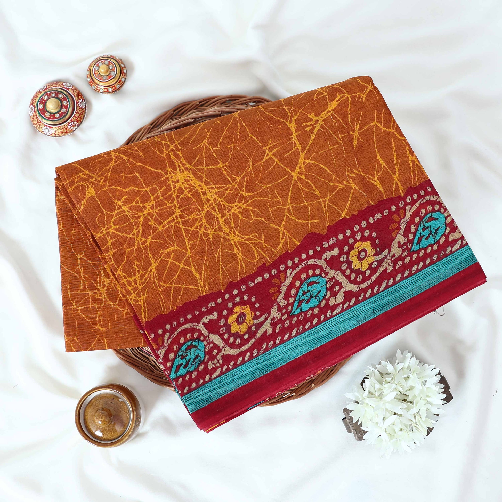 Brown Voile cotton saree with abstract crackle print body and floral contrast red border folded top view