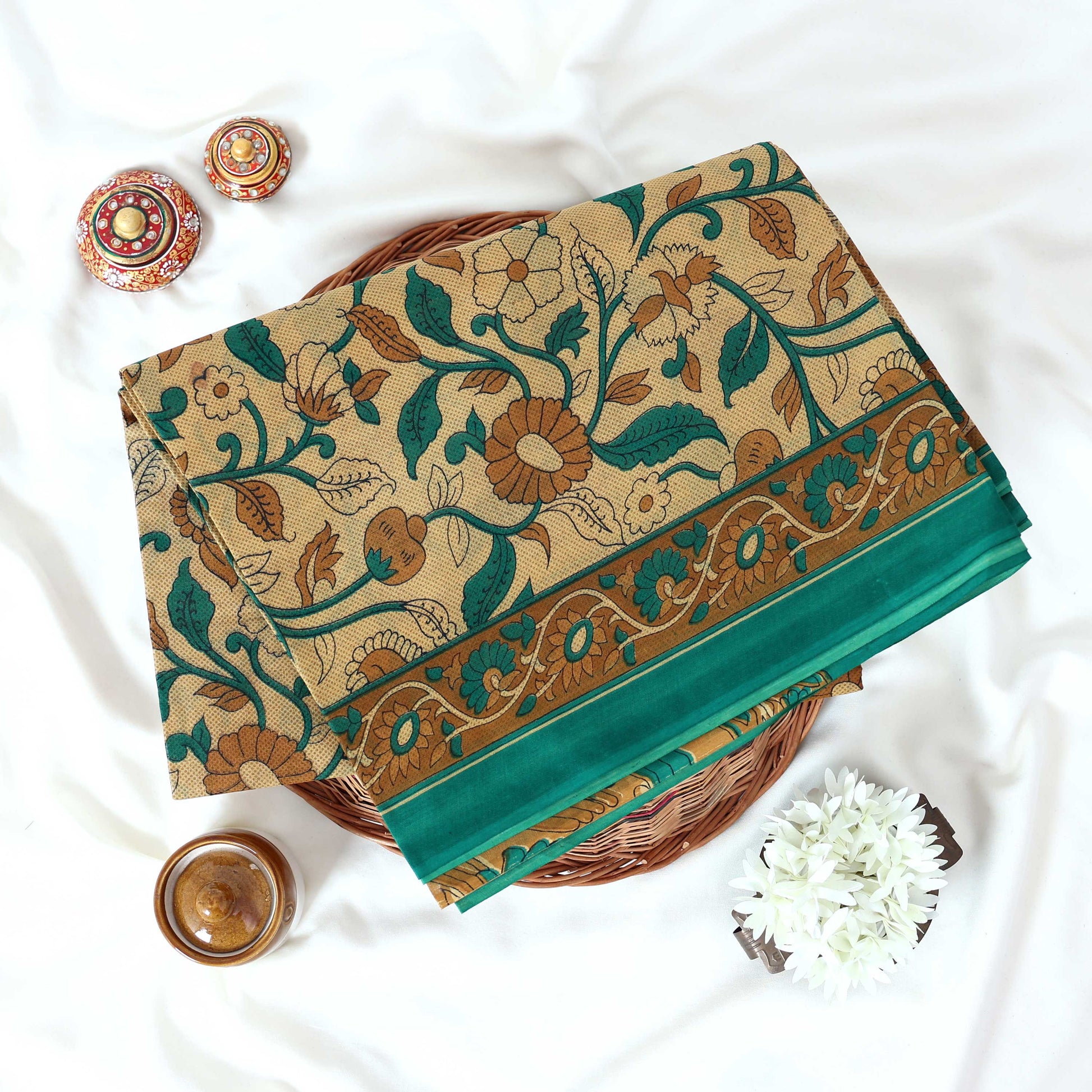 Green Voile cotton saree with floral vine print and contrast border neatly folded in a top view product display.