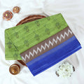 Green voile cotton saree with ikat printed pattern and contrast chevron zari border folded top view display