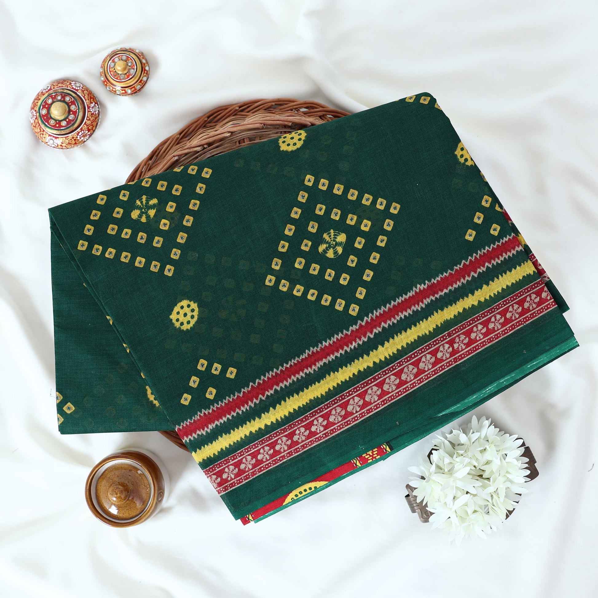 Voile cotton saree with geometric Bandhani inspired motifs and multicolor woven border in green folded top view.