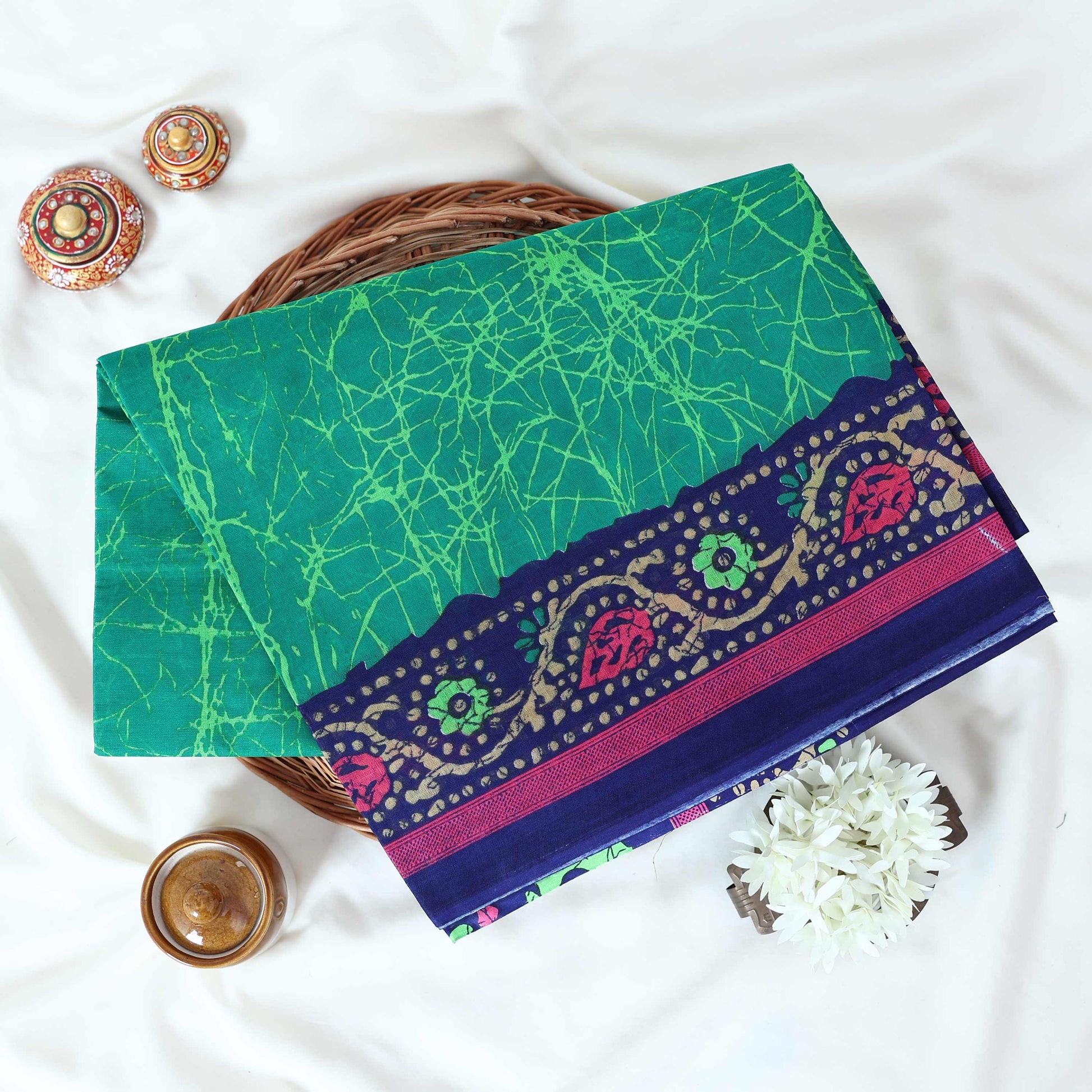 Green Voile cotton saree with abstract crackle print body and floral contrast blue border folded top view