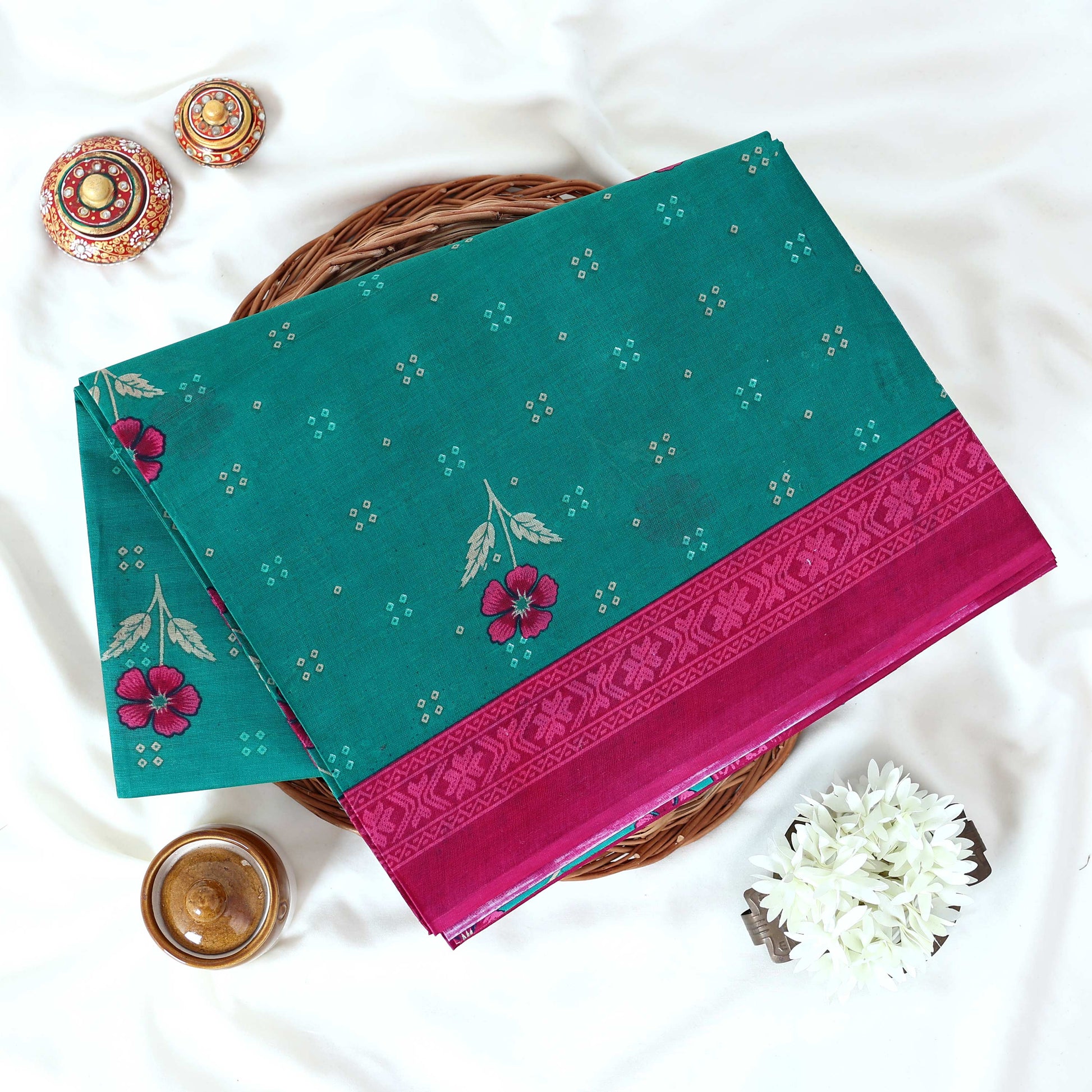 Green Voile cotton saree with floral motifs butta body pattern and pink floral motif border folded top view