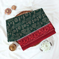 Green Voile cotton saree with tribal print body and red contrast folk art border folded top view 