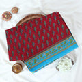 Voile cotton saree with floral motif print and decorative border in maroon folded flat lay view on woven basket.