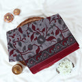 Maroon Voile cotton saree with floral vine print and contrast border, neatly folded in a top view product display.