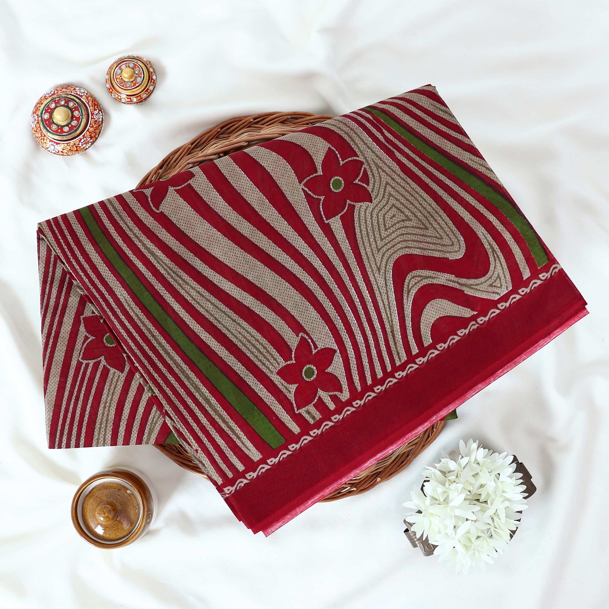 Voile cotton saree maroon floral motifs and wavy white stripe pattern with green accents top view.