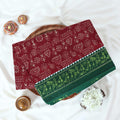 Maroon Voile cotton saree with tribal print body and green contrast folk art border folded top view 