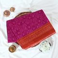 Purple Voile cotton saree with spiral and floral printed motifs contrast border front flat lay view on a woven basket.