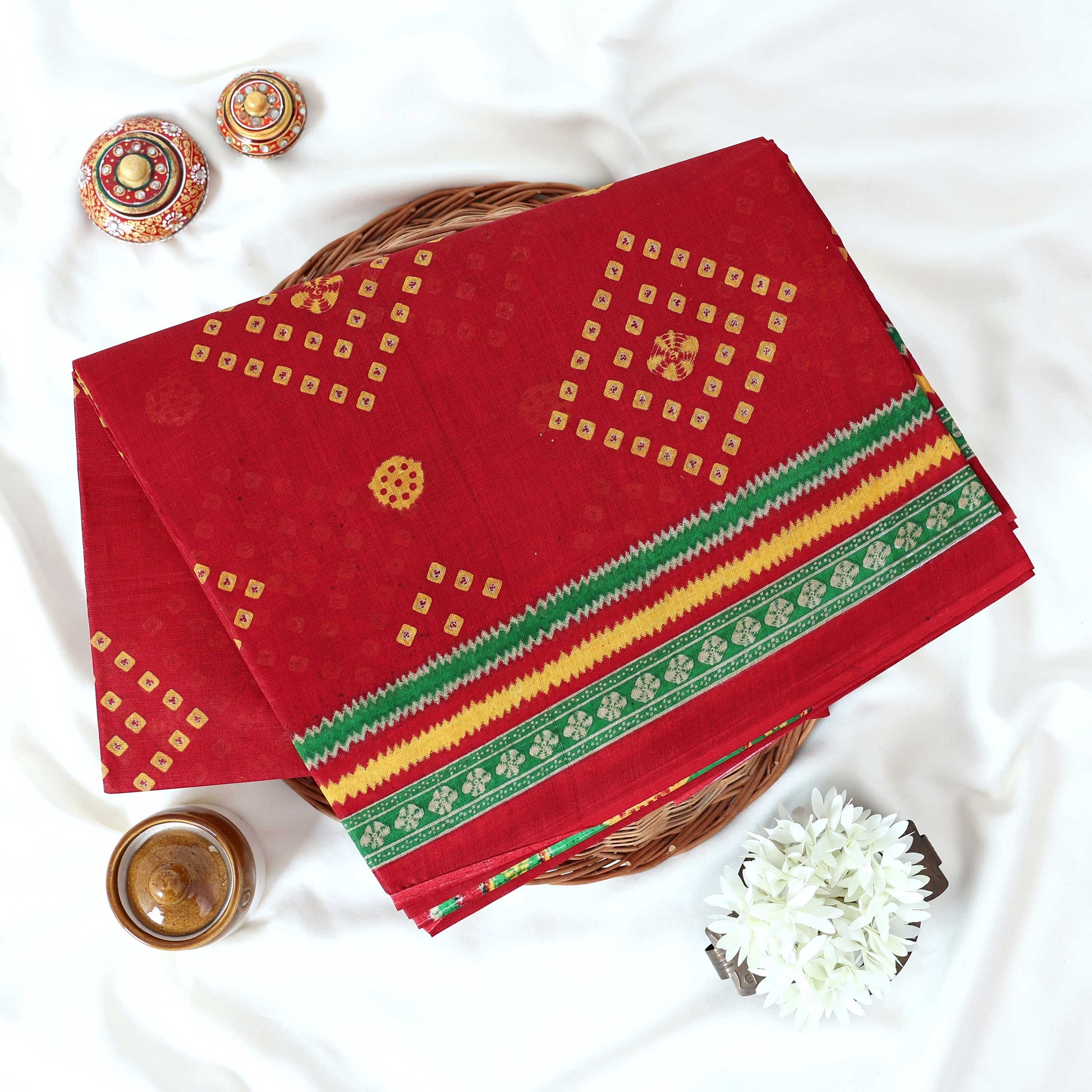 Voile cotton saree with geometric Bandhani inspired motifs and multicolor woven border in red folded top view.