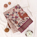 A folded beige cotton saree with a brown deer and floral vine print, displayed 