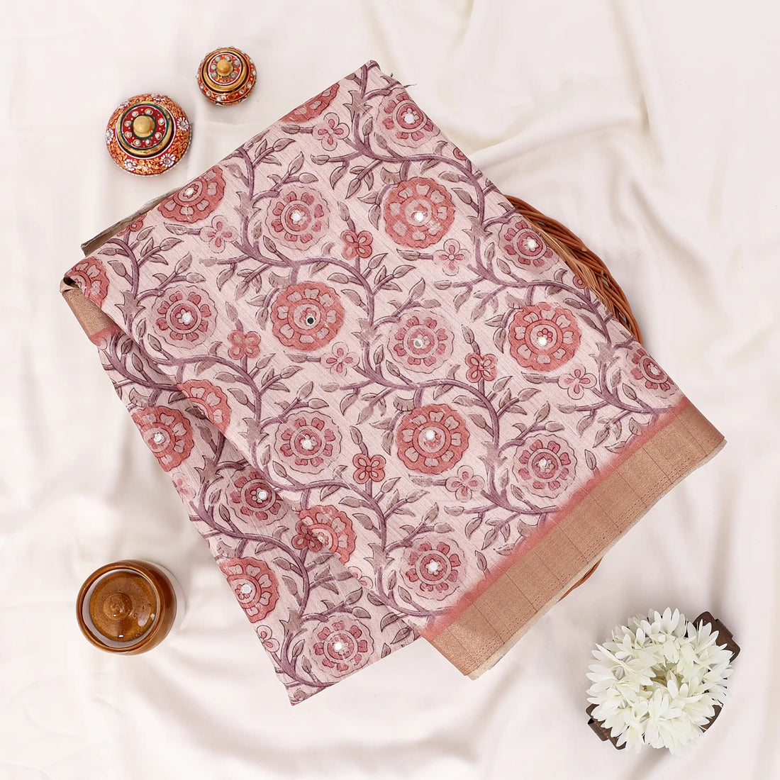 A traditional Indian saree features a rust-red and beige floral block print pattern with a solid rust-red border and a metallic gold zari.