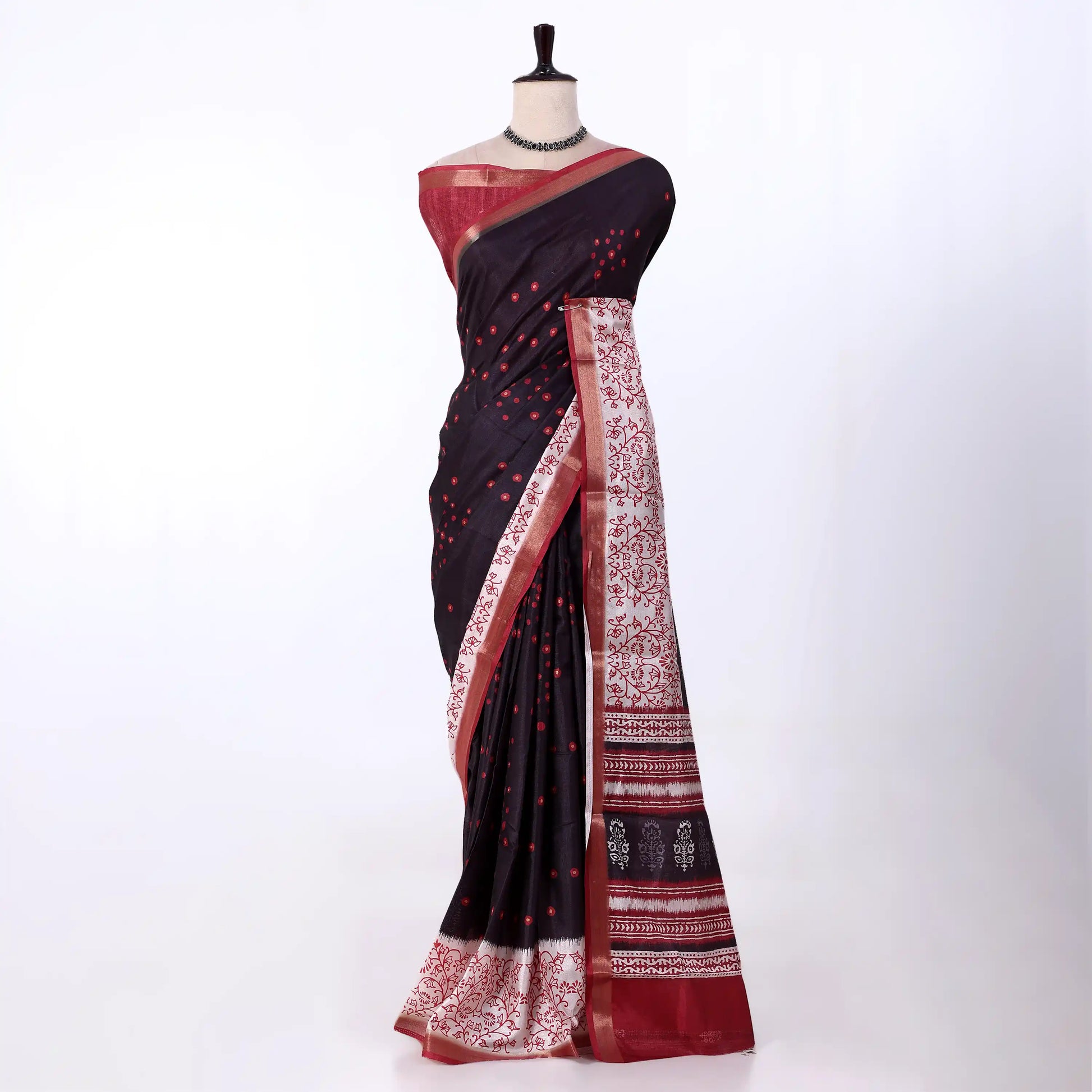 A black and red saree features a black body with red polka dots, a red border, and a white patterned pallu with red accents.