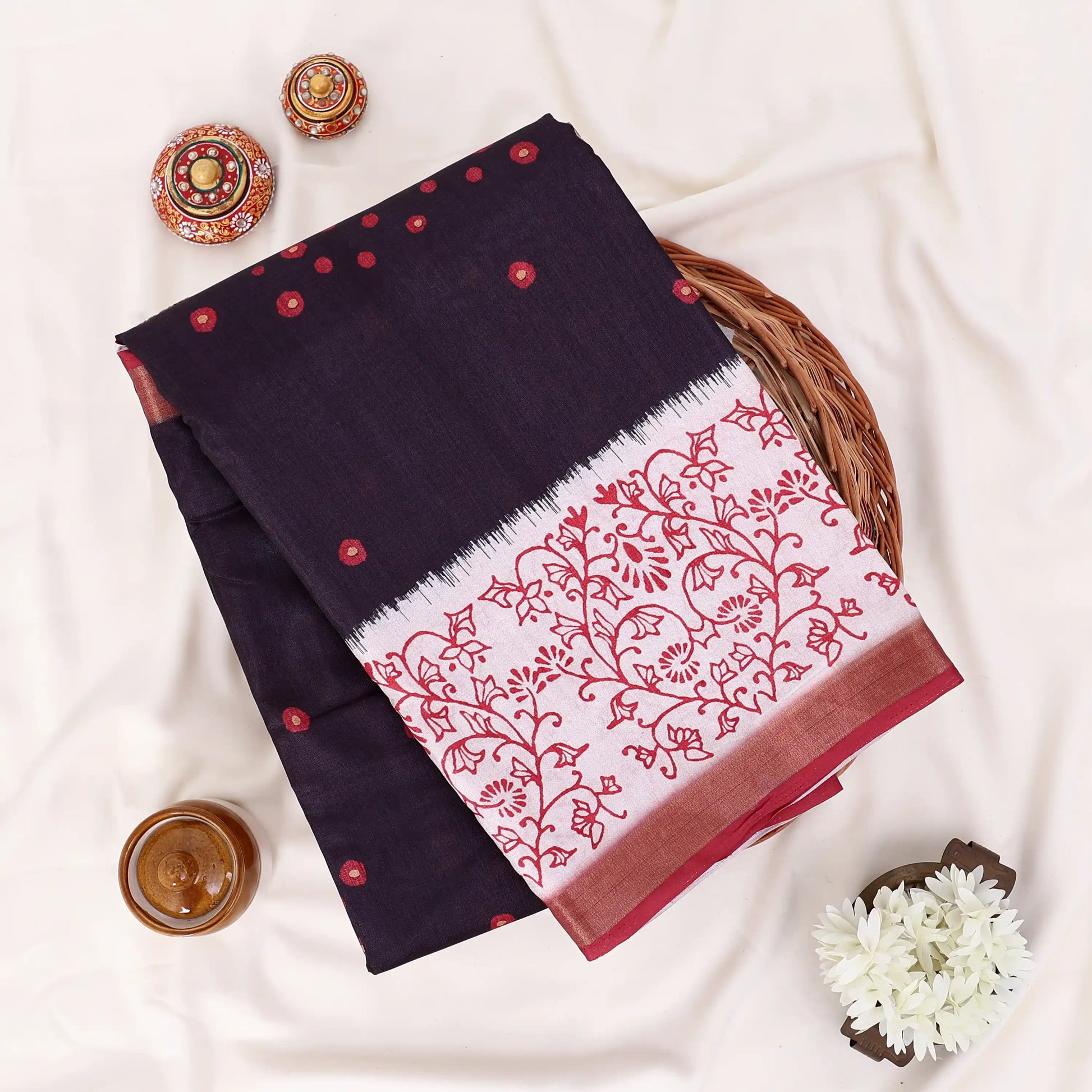 A folded dark navy saree with red floral block print and red border details