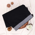 A folded black saree with a wide gray border and small black tassels