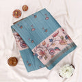 A teal blue and beige printed saree with matching border folded top view