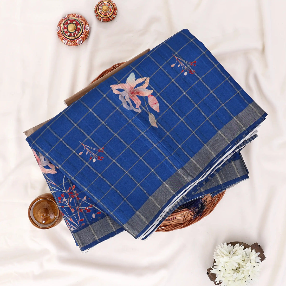 A blue cotton saree with pink floral prints and a gray plaid border