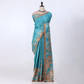 A blue saree with intricate gold and brown paisley patterns