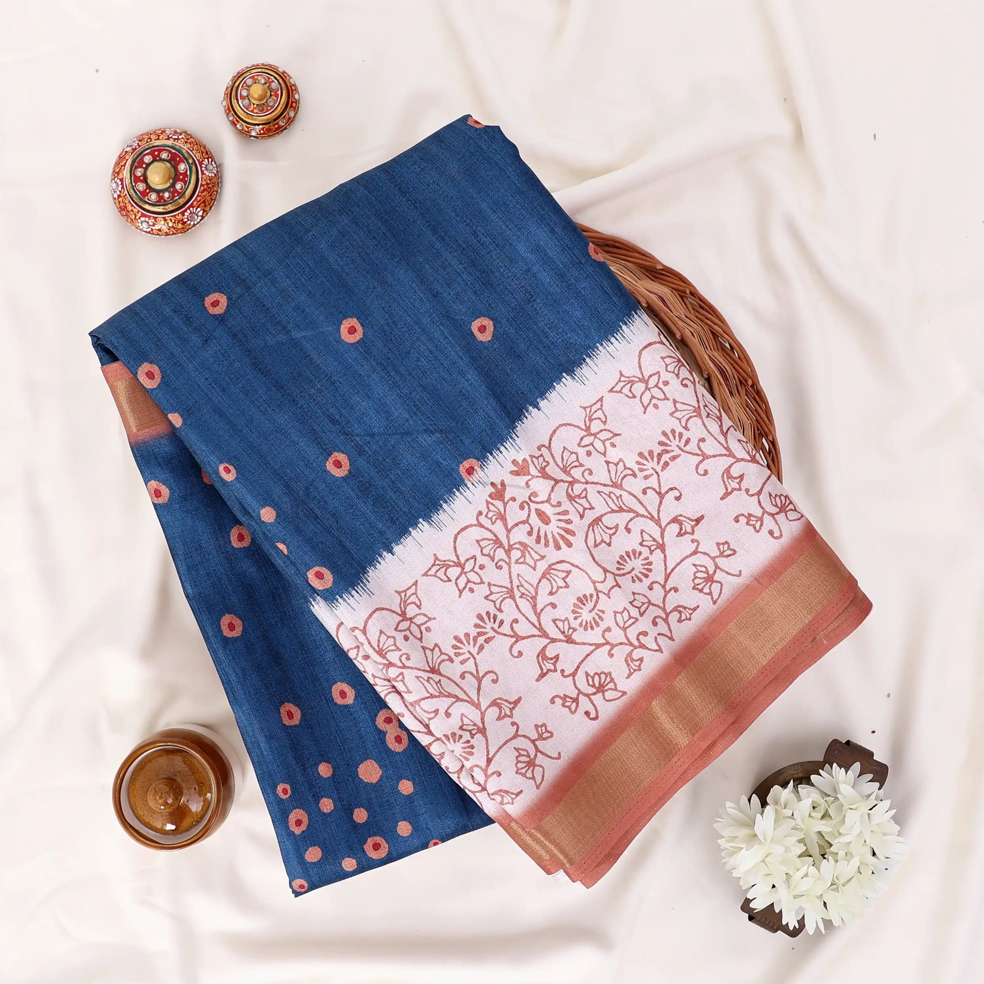 A blue saree with coppery brown borders and white printed patterns