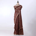 A deep brown saree with intricate gold and beige floral patterns