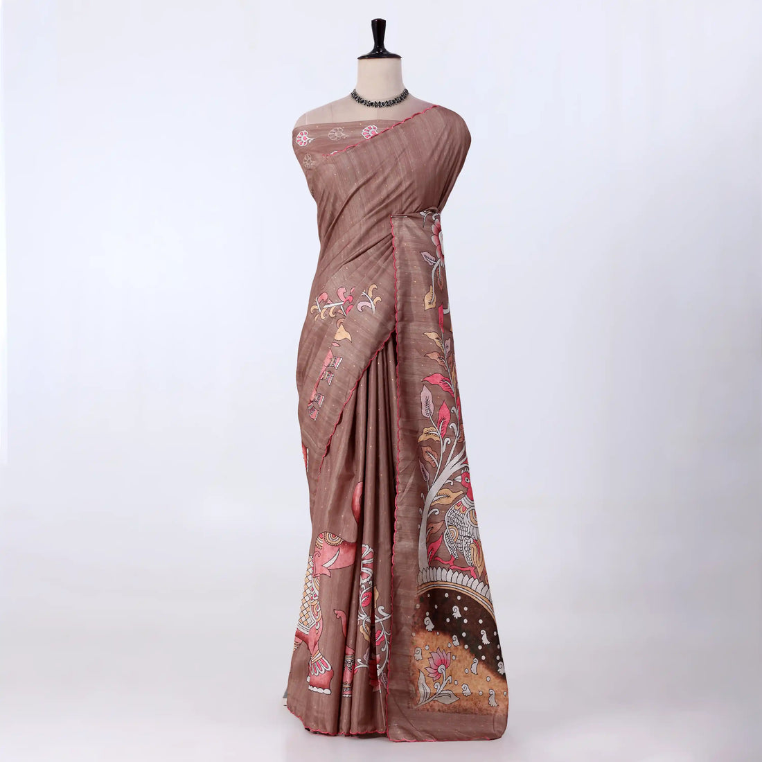 A brown saree with intricate floral and paisley patterns in pink, gold, and white