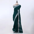 A dark green saree with a silver border and pallu