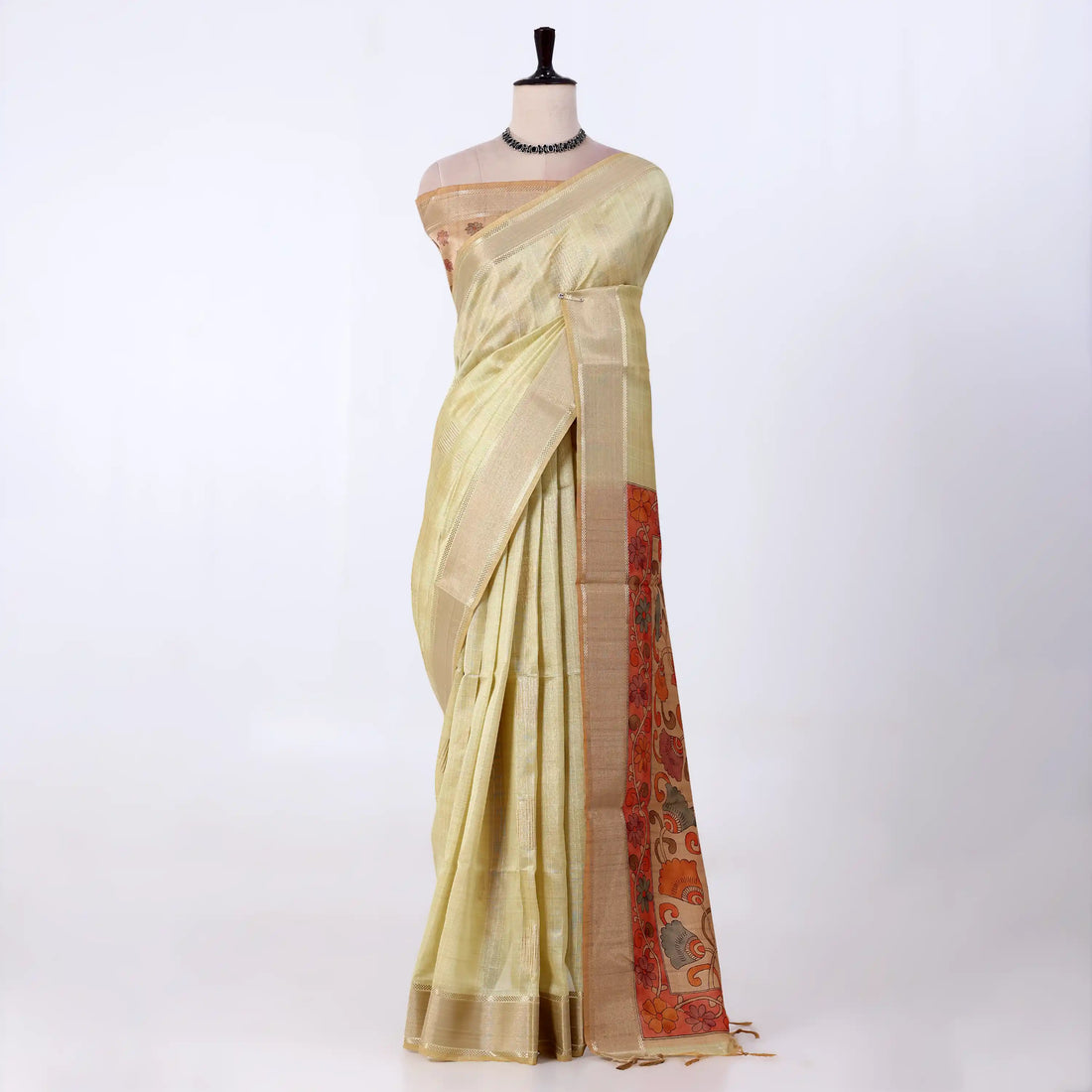 A light yellow saree draped featuring a wide beige border and a red patterned pallu