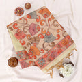 A folded light yellow saree draped featuring a wide beige border and a red patterned pallu