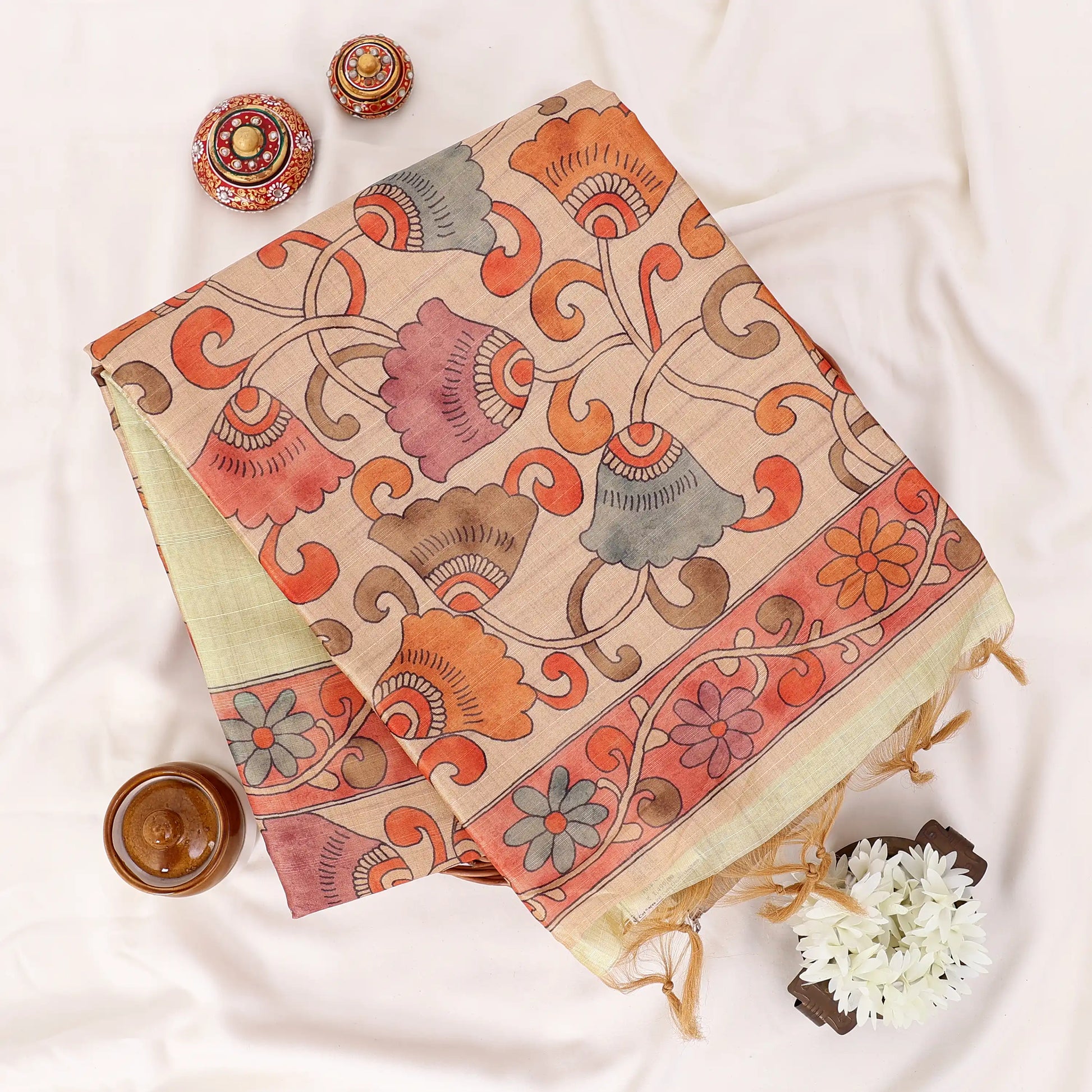 A folded light yellow saree draped featuring a wide beige border and a red patterned pallu