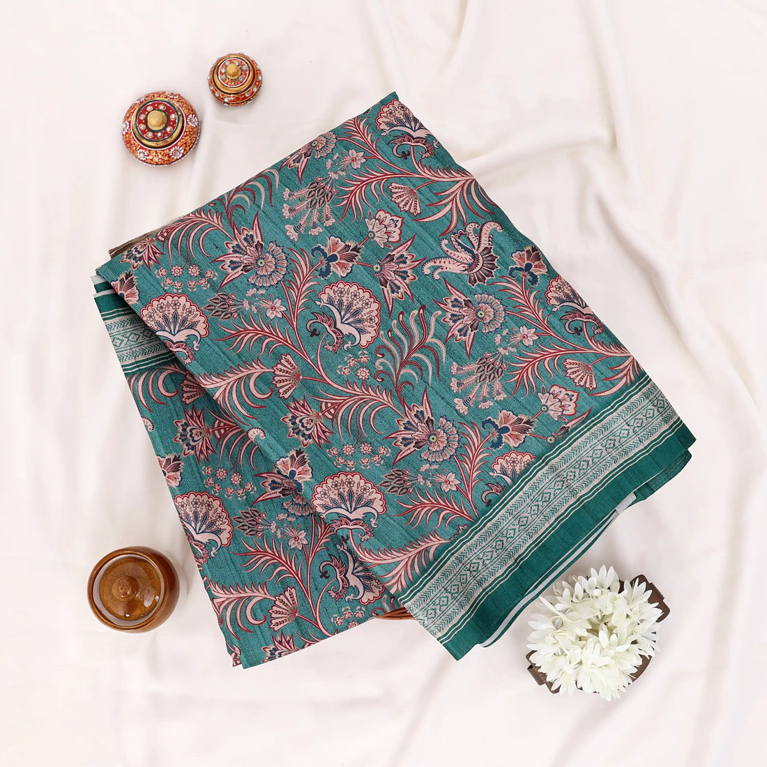 A dark green saree with intricate red and pink floral patterns and a striped border