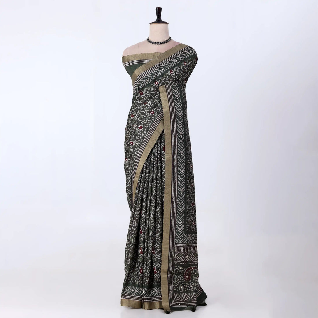 A black and olive green patterned saree with a beige border