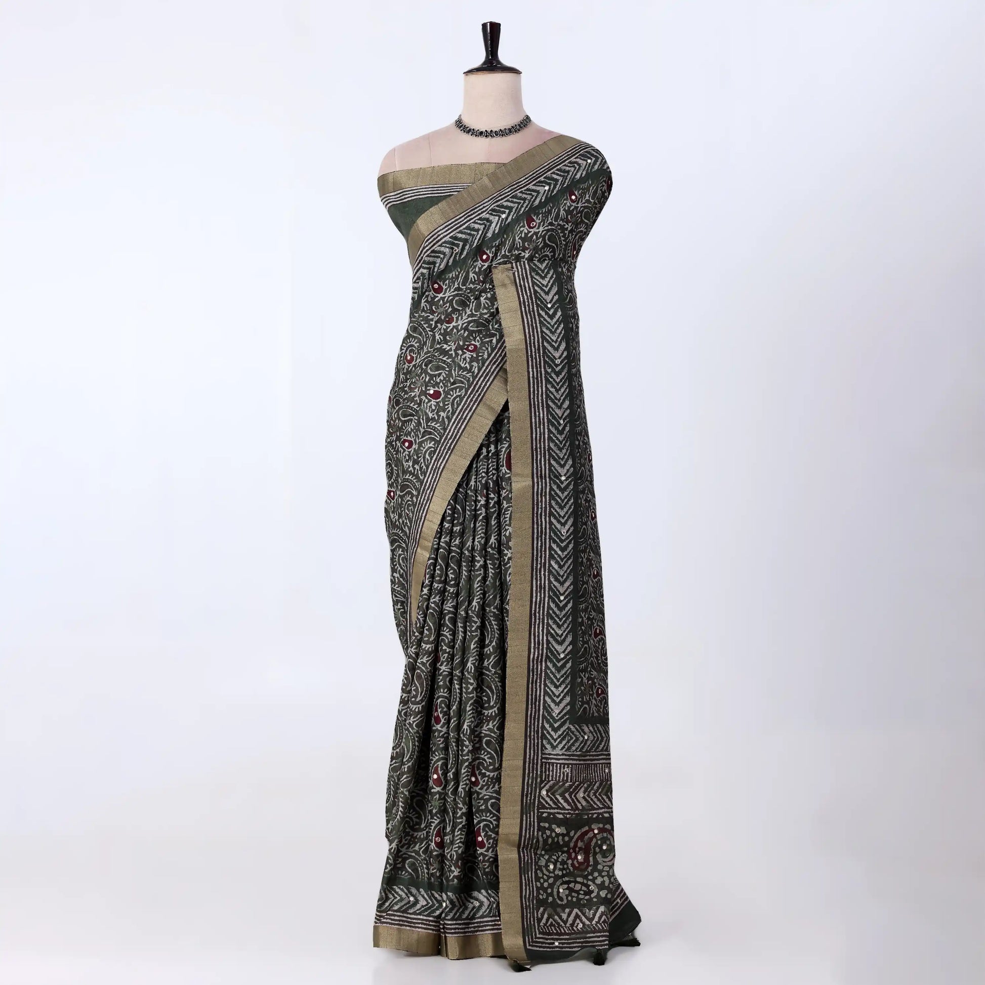 A black and olive green patterned saree with a beige border