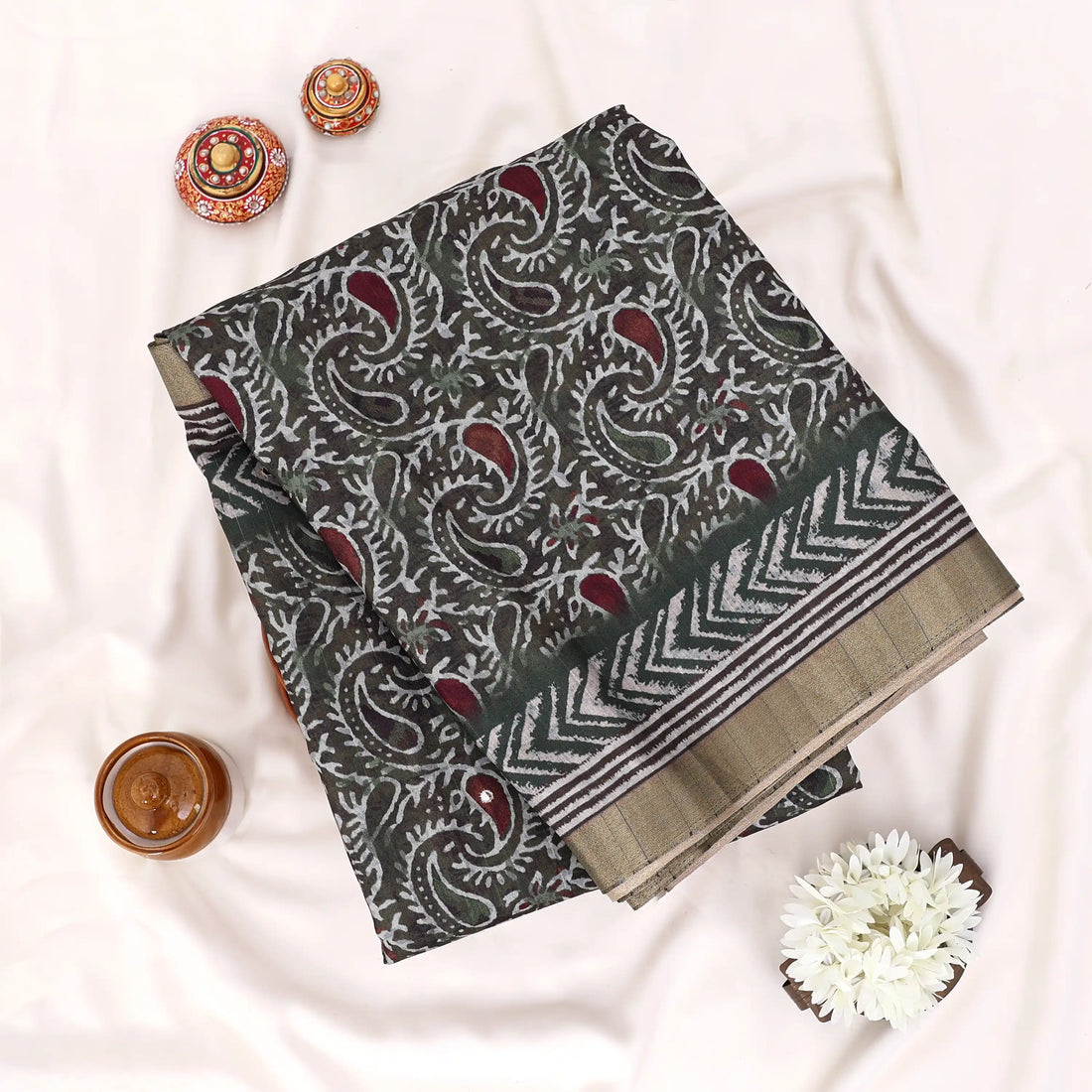 A black and olive green patterned saree with a beige border