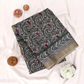 A folded patterned fabric piece with a dark gray base, white paisley and chevron motifs