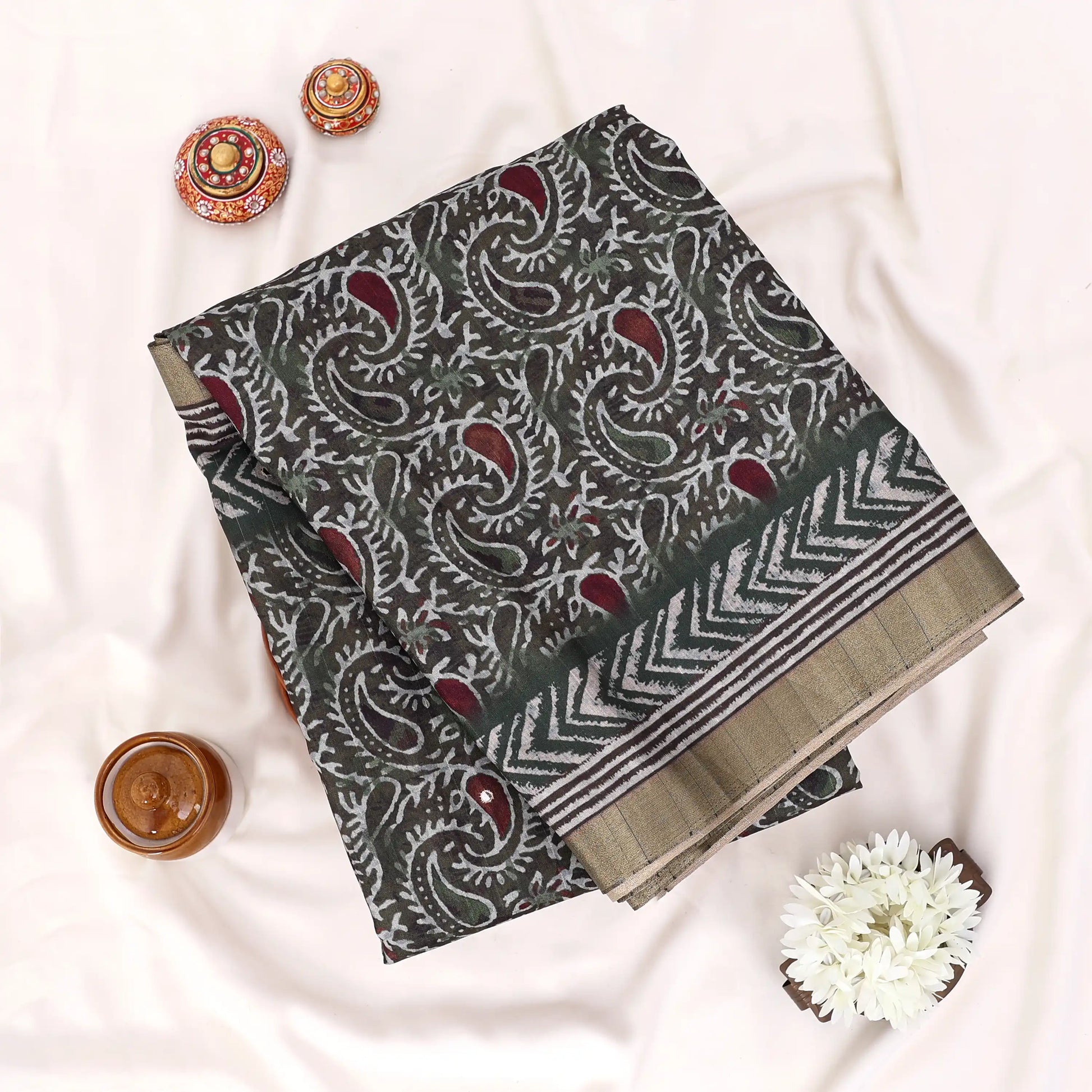 A folded patterned fabric piece with a dark gray base, white paisley and chevron motifs