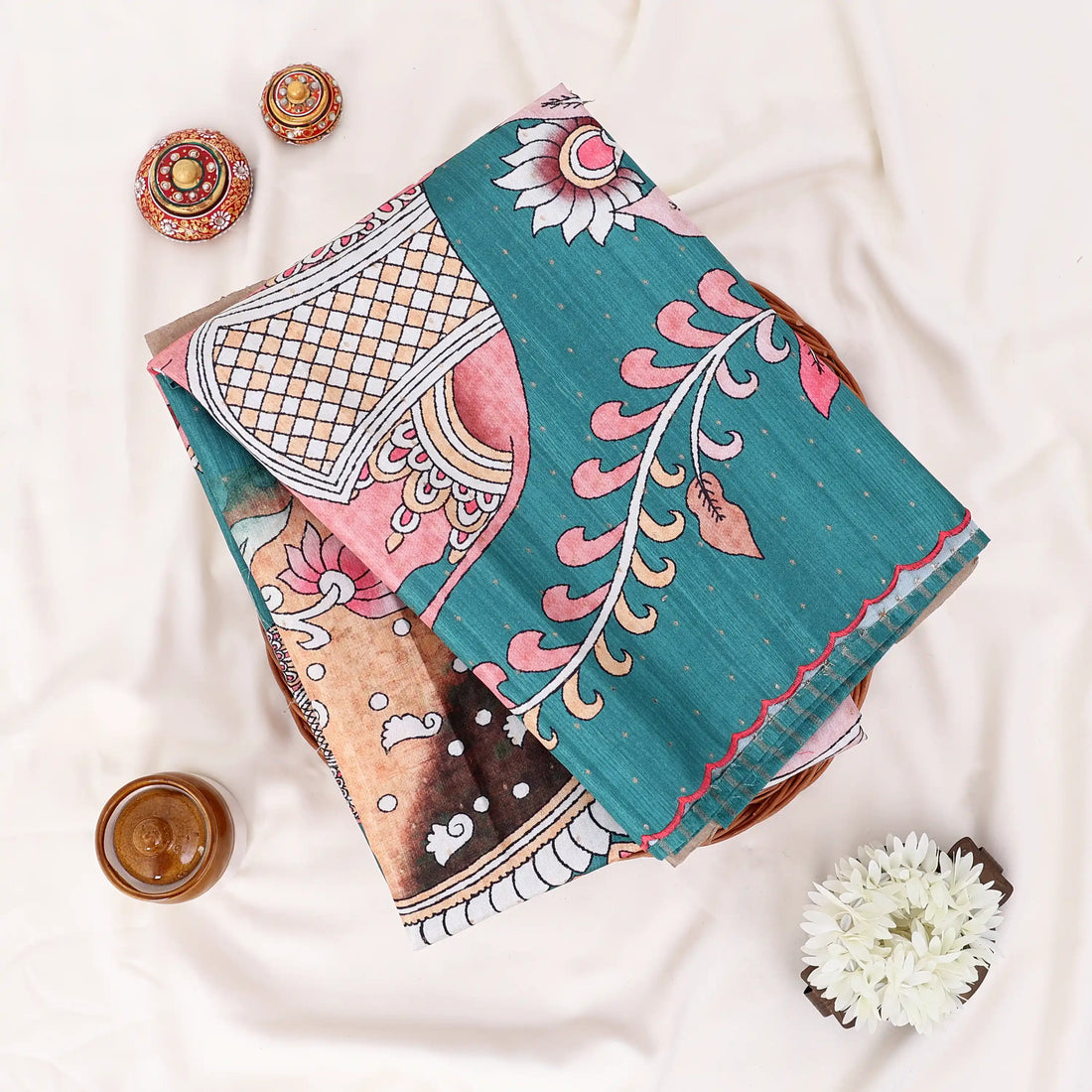 A teal green saree with red and pink floral and bird motifs